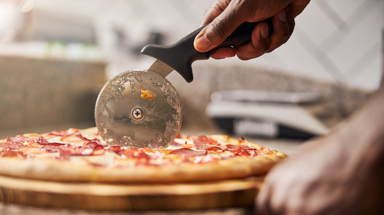 Hand cutting pepperoni pizza