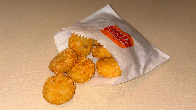 Round hash brown medallions pouring out of a paper bag on countertop.