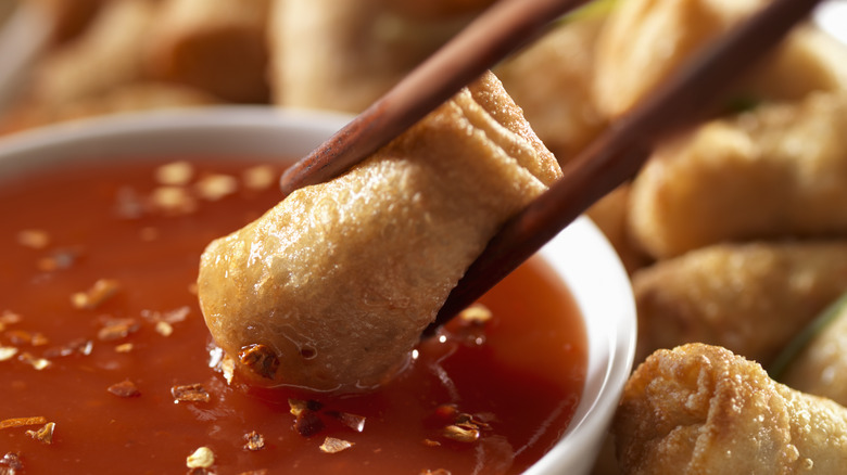 Egg rolls being dipped in plum sauce