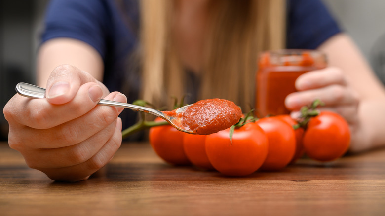 A hand holding homemade ketchup on a spoon