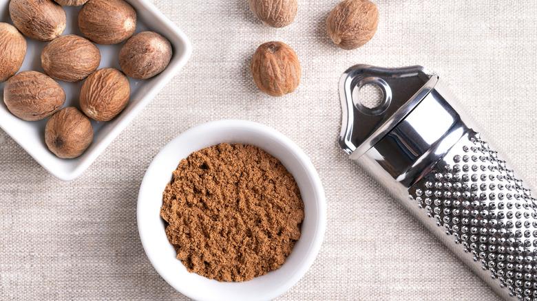 Whole nutmegs and a bowl of ground nutmeg powder.