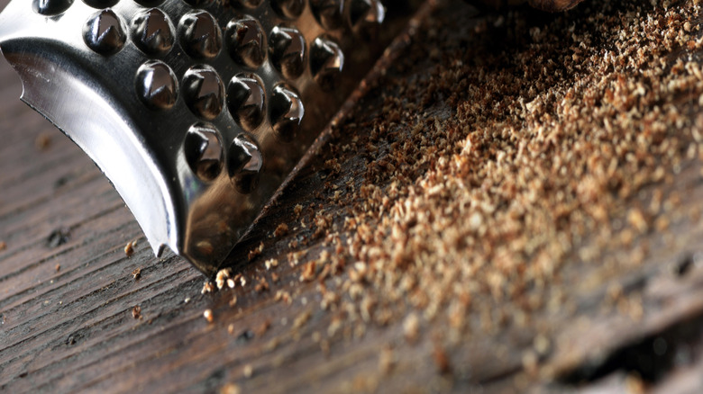 Closeup of a piece of nutmeg, half shaved with a metal grater.