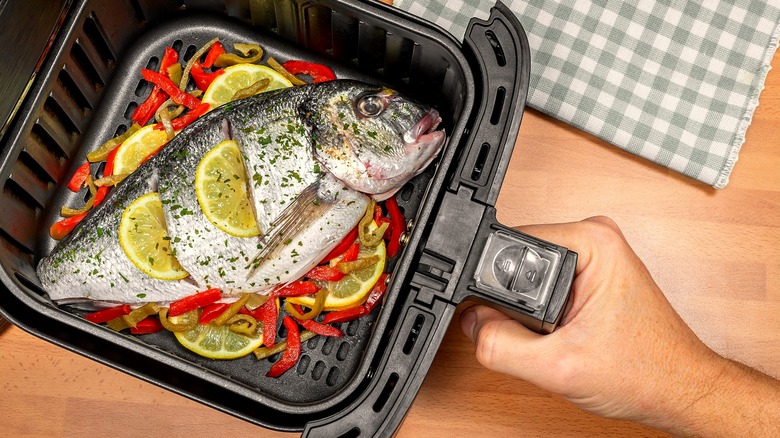 Whole fish in the basket of an air fryer with lemon