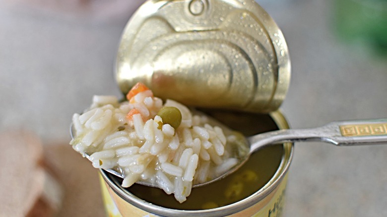 Spooning rice and vegetable soup out of an open can