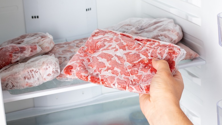 Hand removing frozen meat from freezer