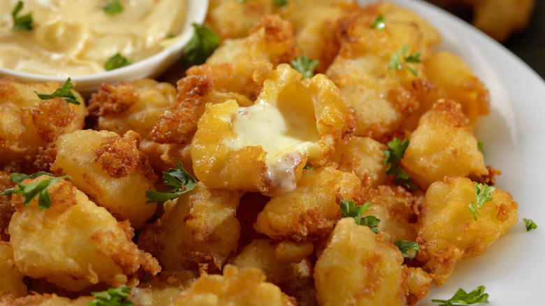 Deep fried cheese curds next to dipping sauce