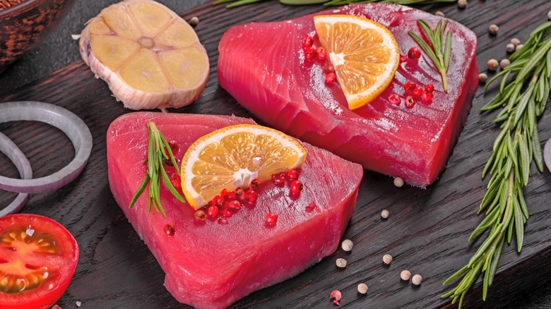 Raw tuna steaks seasoned with garlic, pink peppercorns, rosemary, and citrus