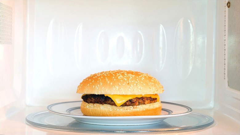 Fast food sandwich on a ceramic plate in a white microwave