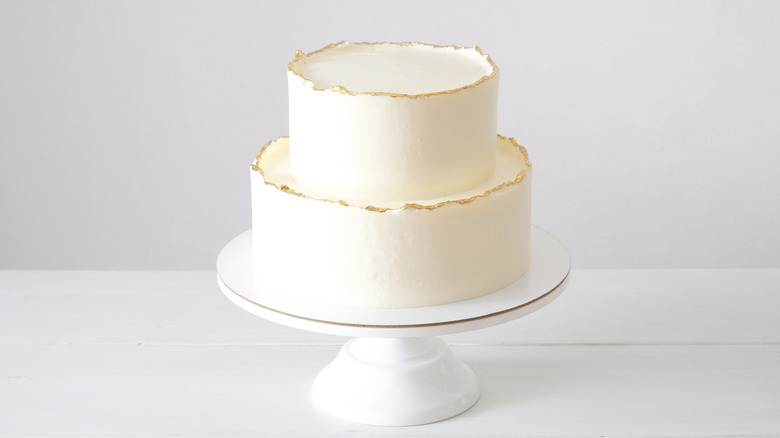 Two-tier wedding cake with white frosting and gold trim