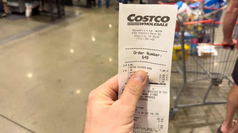 Person's hand holding a Costco receipt