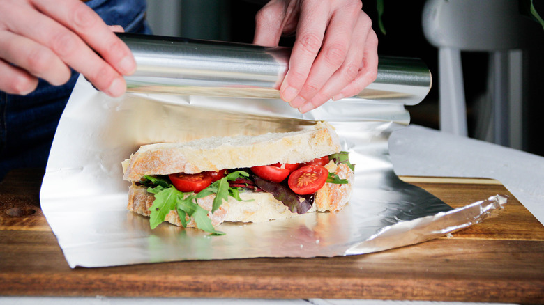 Person wrapping a sandwich in aluminum foil