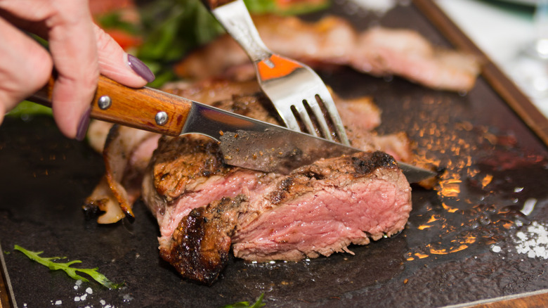 Person cutting a steak with a sharp steak knife