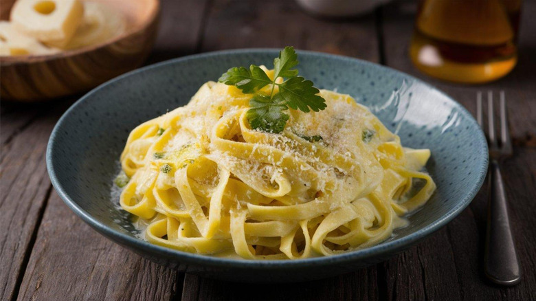 A plate of lightly sauced Alfredo pasta topped with grated cheese.