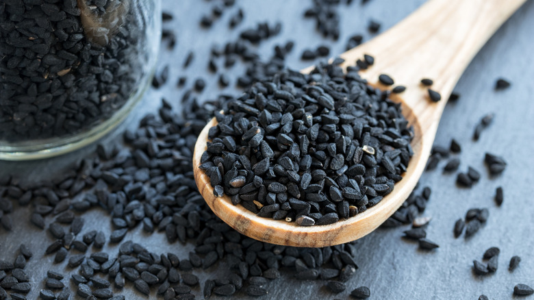 A wooden spoon full of small black nigella seeds