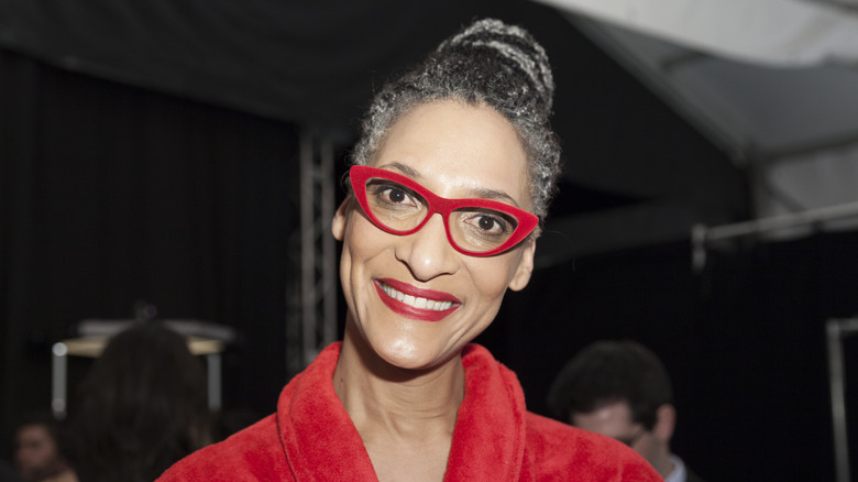 Carla Hall smiling and wearing red glasses