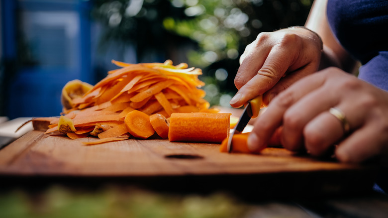 Close up of person slicing carrots on cutting board