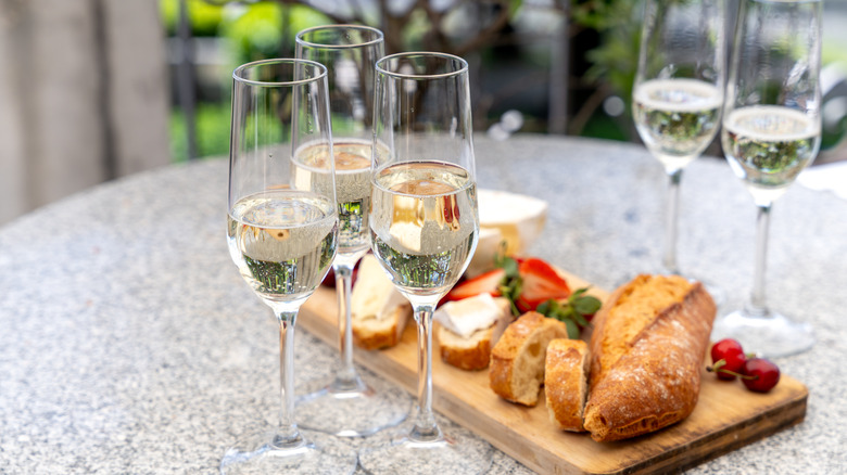 Bread and cheese on a wooden board with glasses of Champagne