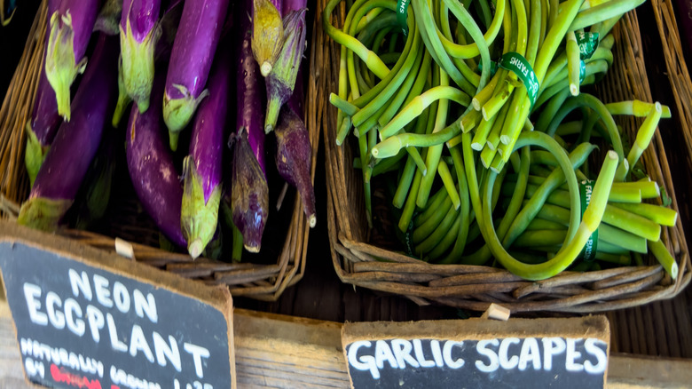 Garlic scapes next to eggplants in the grocery store