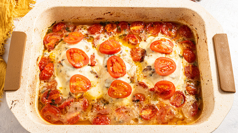 Baking dish with melted mozzarella and cherry tomatoes cooked in sauce