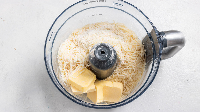 Food procesor with shredded cheese, cubed butter, and flour