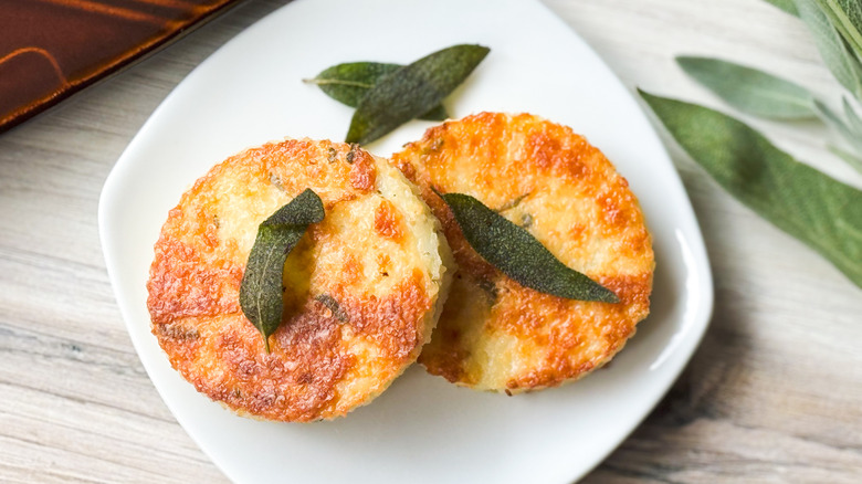 Cheesy truffled grit cakes on plate with fried sage