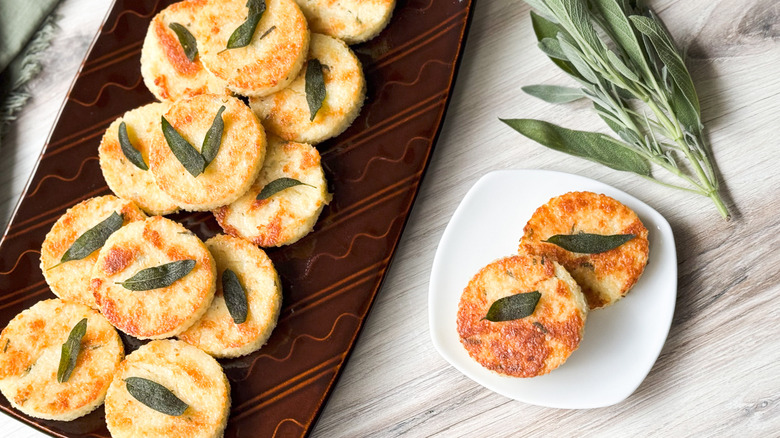 Cheesy truffled grit cakes on serving platter with fresh sage sprig