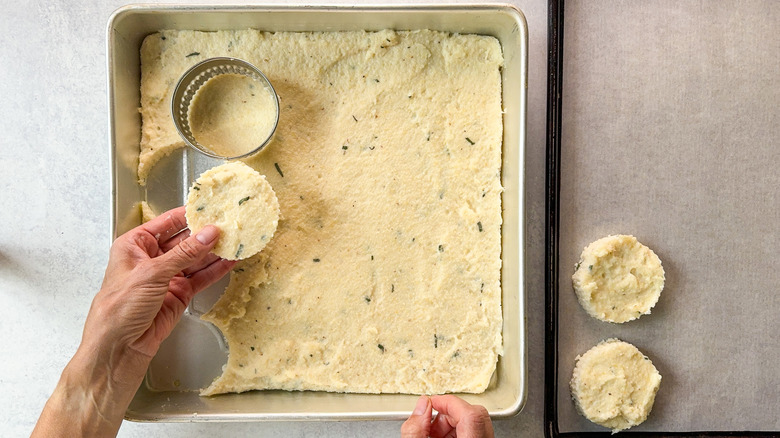 Cutting chilled cheesy truffled grits into rounds with cookie cutter