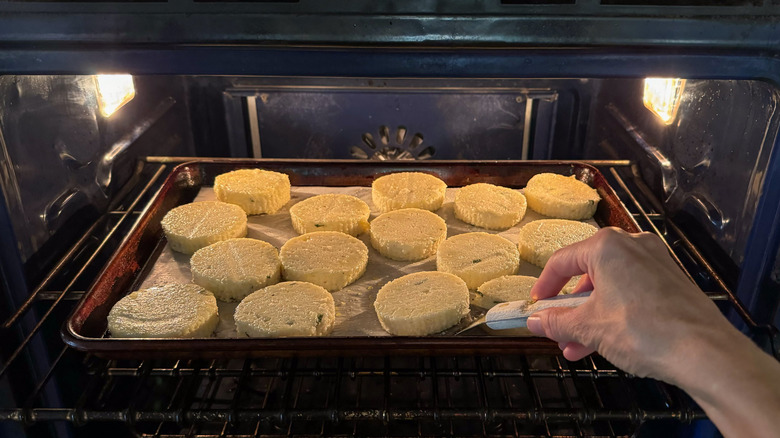 Flipping cheesy truffled grit cakes in oven on sheet pan with spatula