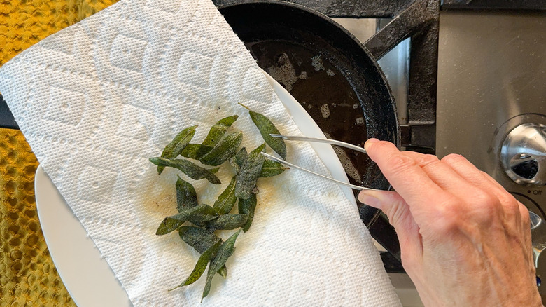 Fried sage leaves draining on paper towel