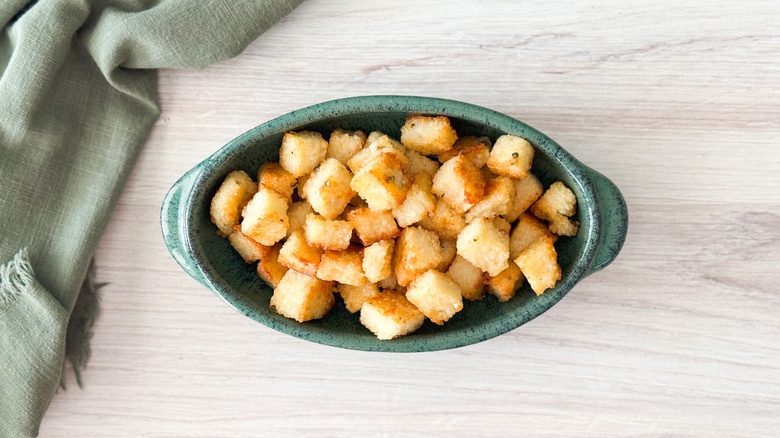 Cheesy truffled grit cakes scraps made into croutons in serving dish