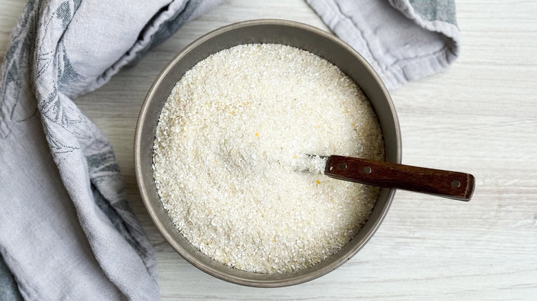 Quick-cooking white grits in bowl with spoon and towel