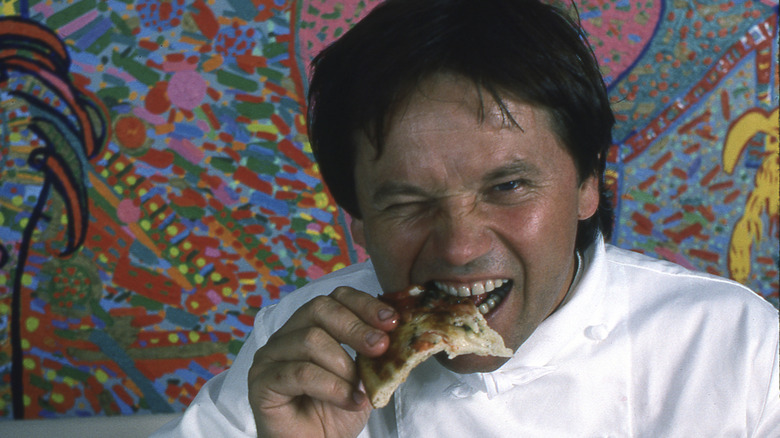 Wolfgang Puck takes a bite of one of his signature dishes, Smoked Salmon Pizza