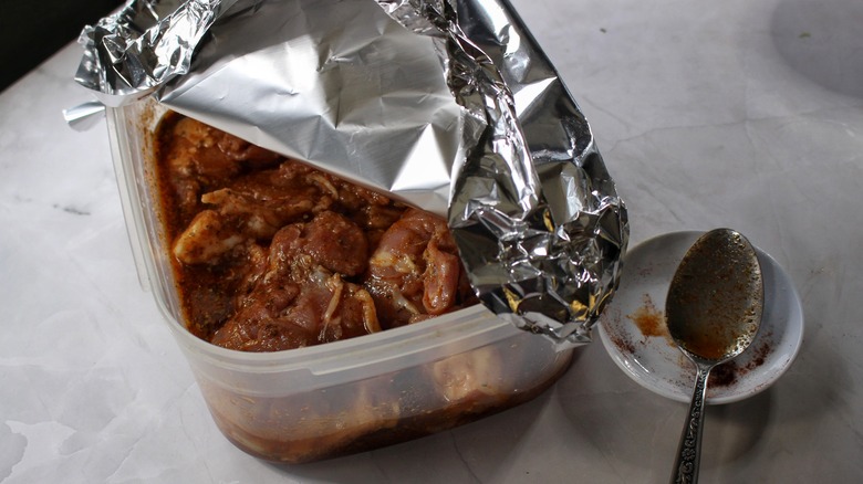 covered tub of marinating chicken