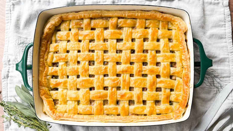 Baked chicken, mushroom, and winter squash pot pie with lattice puff pastry crust in casserole dish