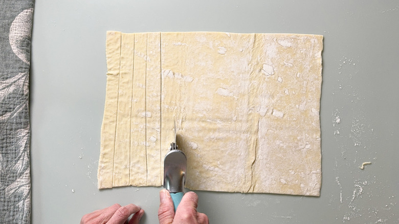 Cutting puff pastry into strips with a pizza cutter