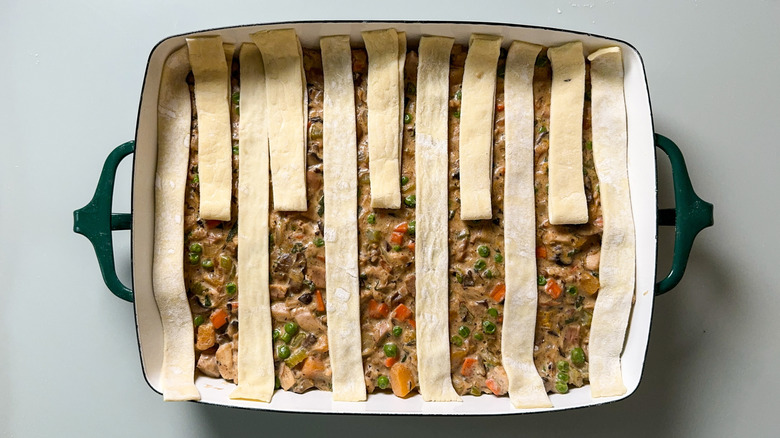 Puff pastry dough strips folded back on top of pot pie filling in casserole dish