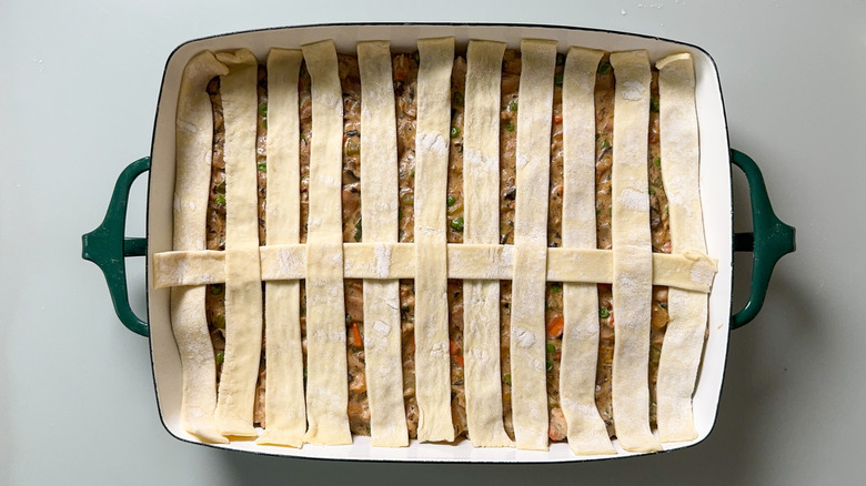 Making a lattice with puff pastry strips over pot pie filling in casserole dish