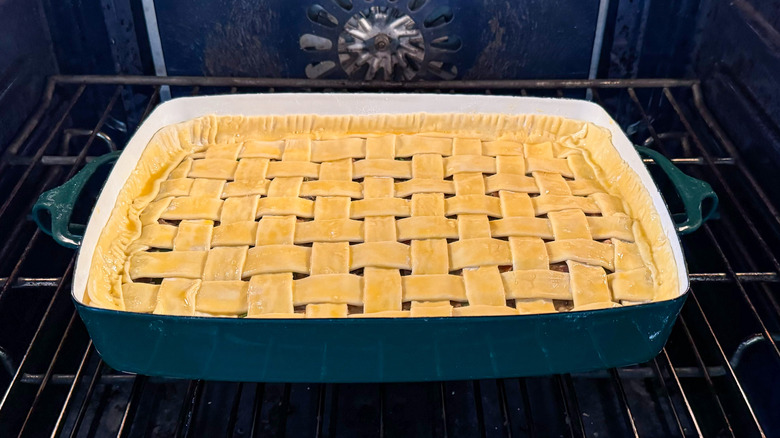 Chicken, mushroom, and winter squash pot pie in casserole dish with lattice puff pastry crust baking in oven