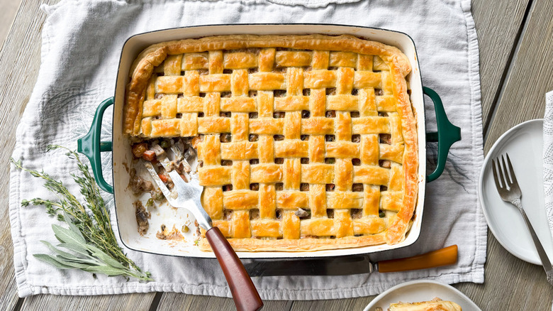 Chicken, mushroom, and winter squash pot pie with one piece cut out and serving spatula