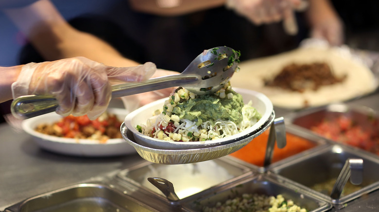 Close-up of Chipotle worker scooping guacamole onto a burrito bowl