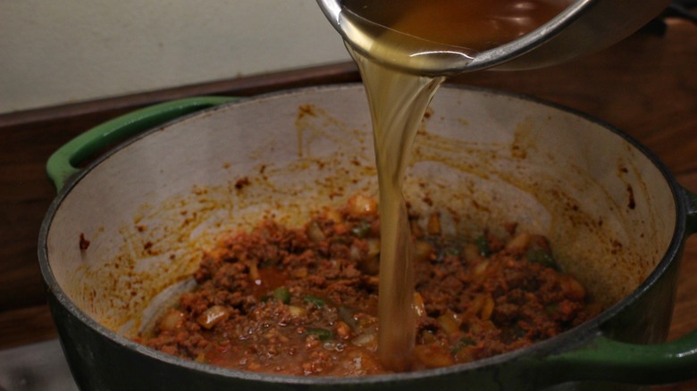 pouring broth into chili pot