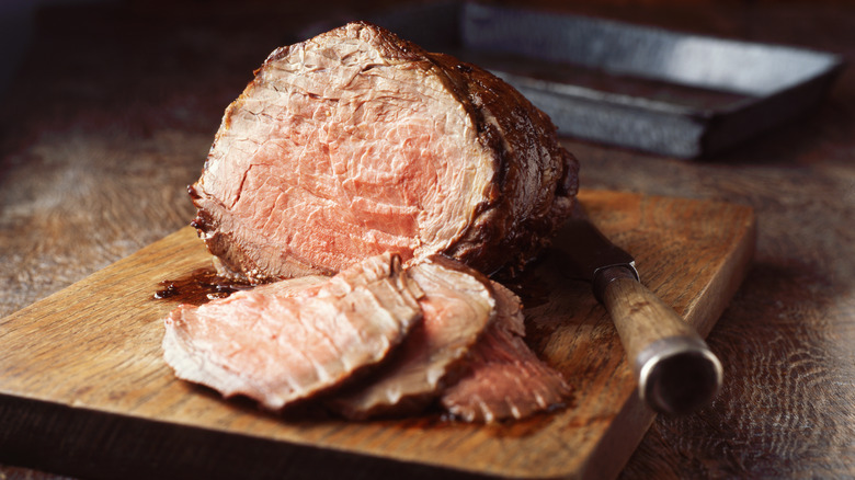 A sliced roast beef on a wooden board