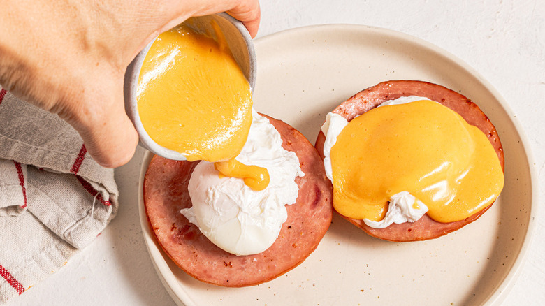 hand pouring sauce on egg