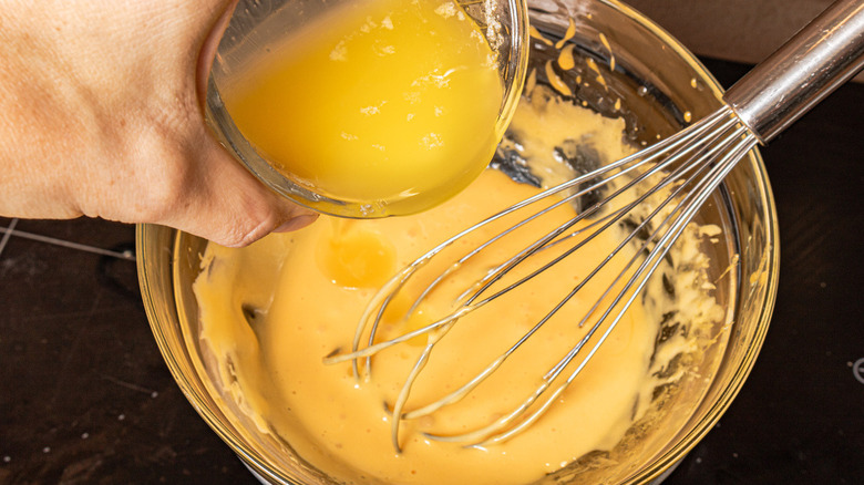 hand pouring butter into eggs