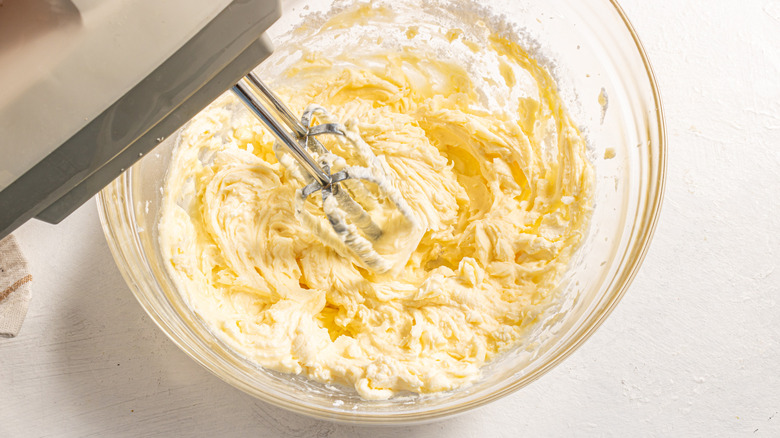 Beating cream cheese frosting with a hand mixer