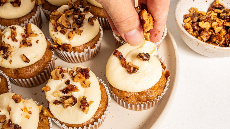 Sprinkling chopped walnuts over cupcakes