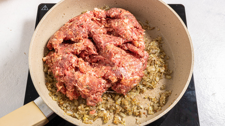 Skillet with chopped onion and ground sausage