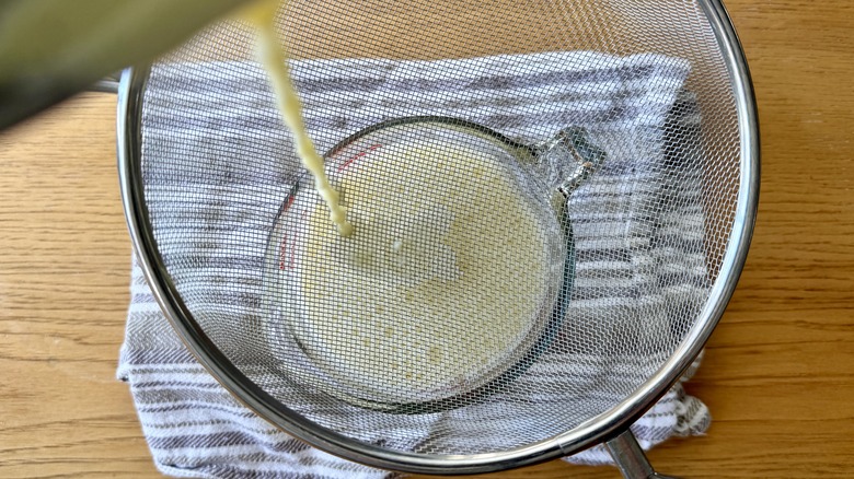 Milk mixture pouring through mesh strainer