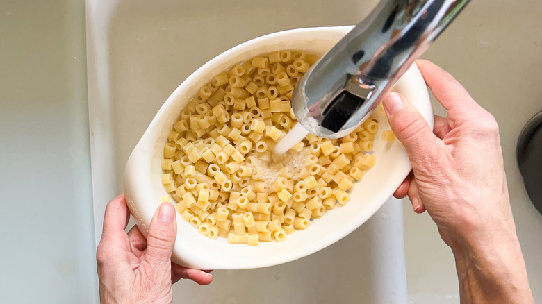 Rinsing ditalini pasta in colander over sink