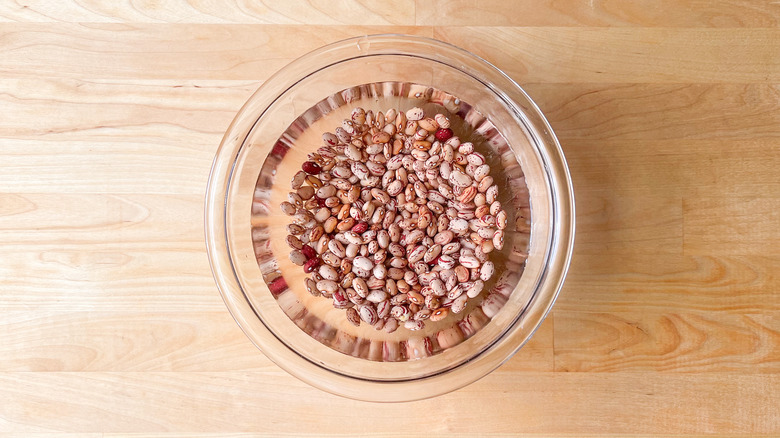 Cranberry beans soaking in bowl of water on table